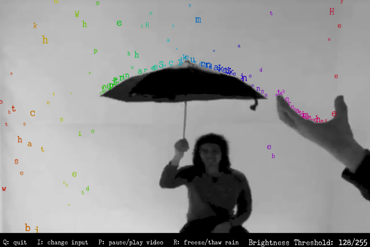 A still frame from the application showing a black and white video where a woman sits in the center holding an umbrella while a hand enters from the right side of the frame in the foreground. Colorful letters descend from the top of the frame and stop when obstructed by a dark object.